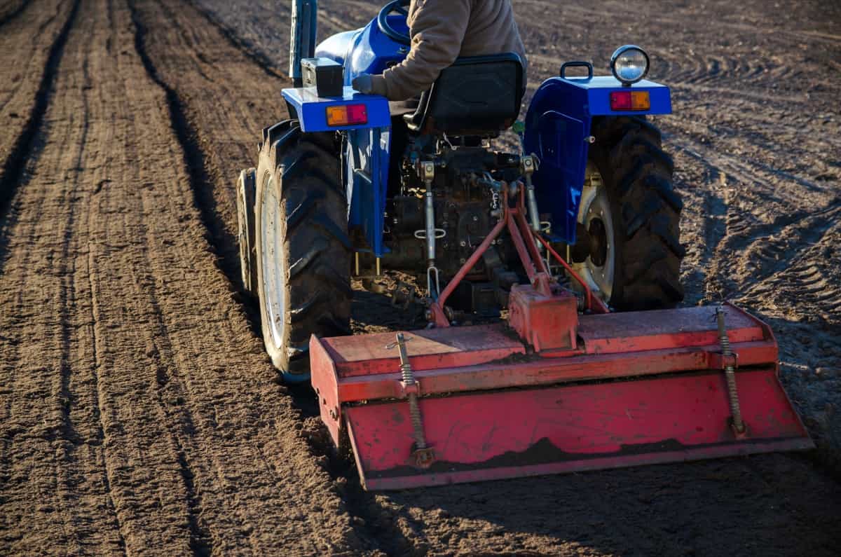 A farmer on a tractor cultivates a farm field